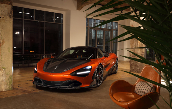 Оранжевый автомобиль  McLaren 720S у дома с креслом