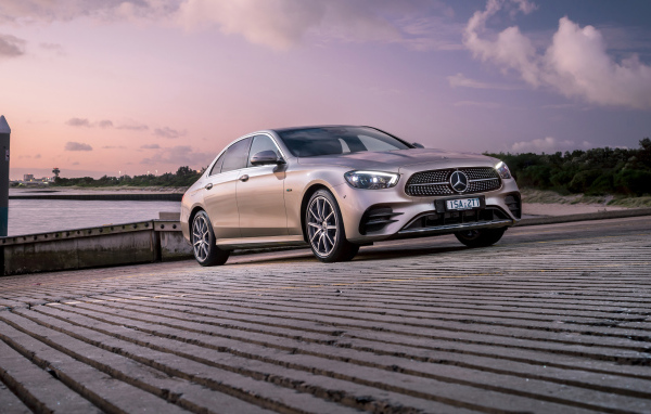 Серебристый автомобиль Mercedes-Benz E 300 E AMG Line 2021 года у реки