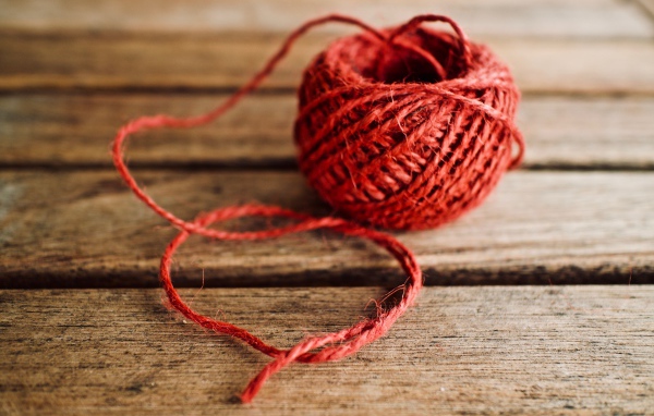 Клубок красной пряжи на деревянном столе 