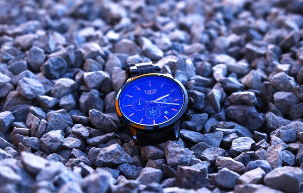 Голубые наручные часы лежат на камнях