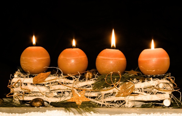 Четыре круглые зажженные свечи на черном фоне