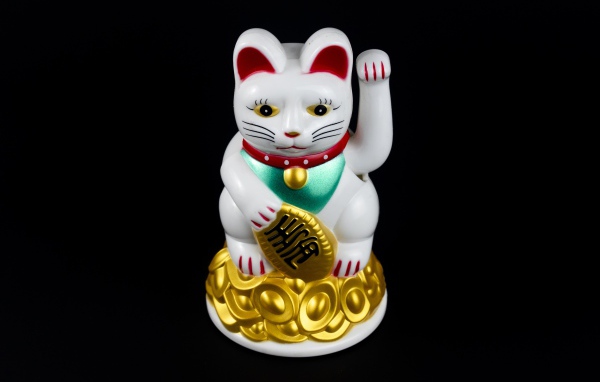 Японская фигурка манэки-нэко кошка на черном фоне