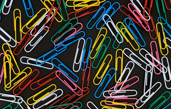 Много разноцветных скрепок на черном фоне