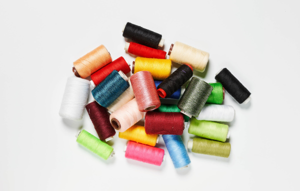 Много катушек разноцветных ниток на белом фоне 
