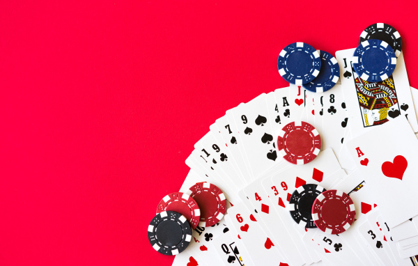 Карты для покера и фишки на красном фоне 