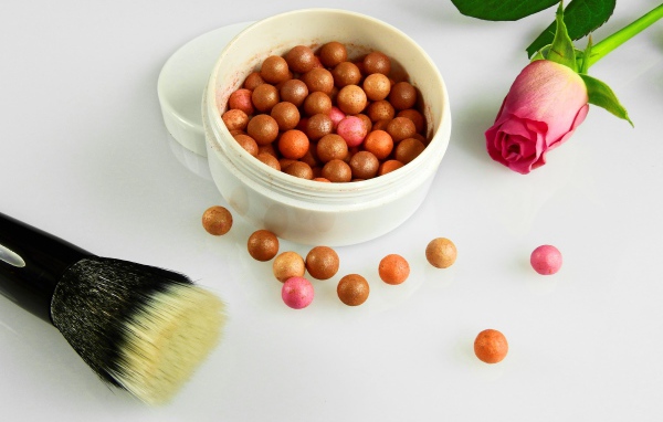 Шариковая пудра на белом фоне с кистью и розой