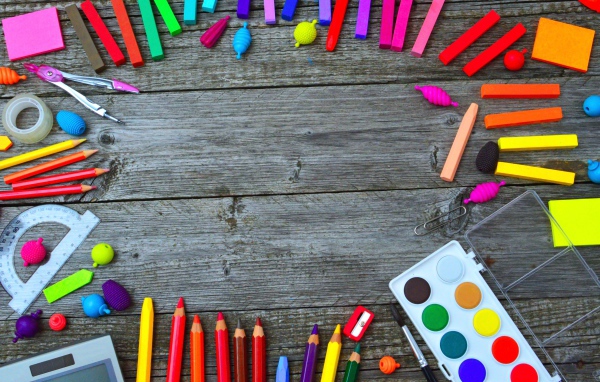 Радуга ярких канцелярских предметов для школы  на деревянном столе