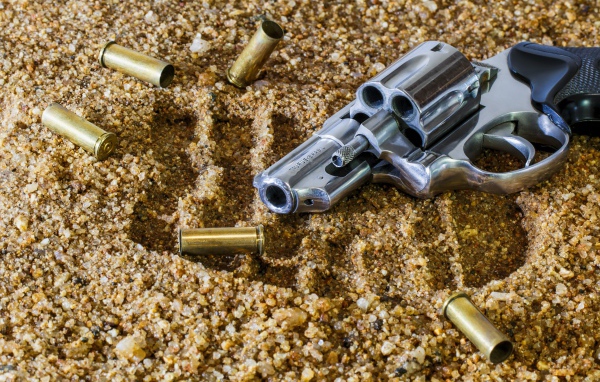 Револьвер с гильзами лежат на песке