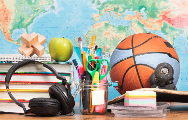 Школьные принадлежности на столе с наушниками и мячом 