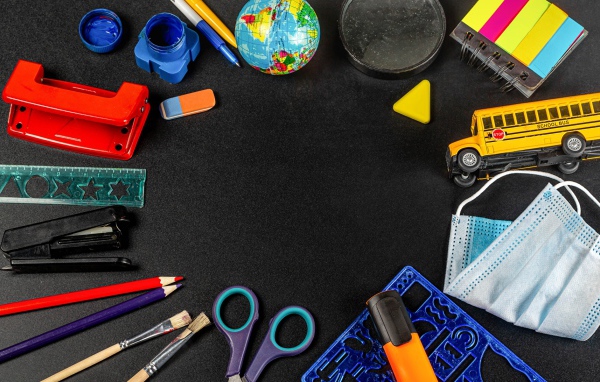 Канцелярские предметы, игрушки и маска на черном столе 