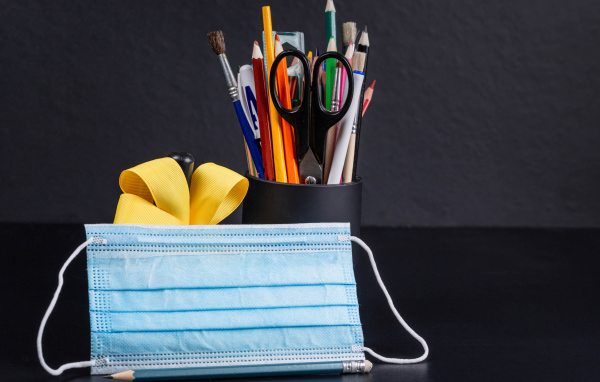 Канцелярские предметы на столе с медицинской маской