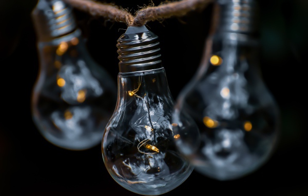 Три лампочки висят на веревке на черном фоне