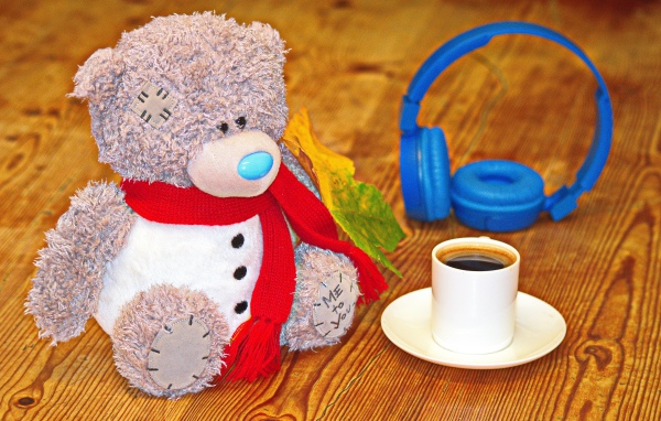 Игрушечный медведь с наушниками и чашкой кофе