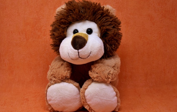 Игрушечный лев на фоне стены