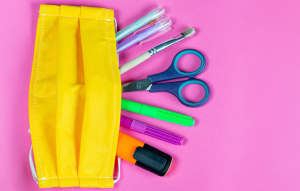 Желтая медицинская маска с ручками и ножницами на  розовом фоне