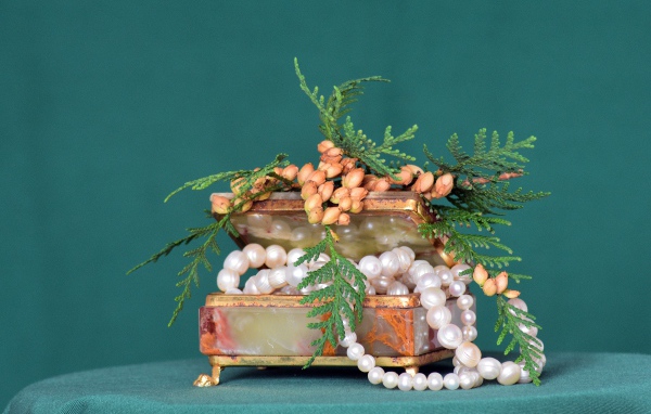 Шкатулка с бусами из жемчуга на зеленом фоне 