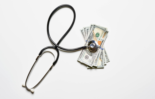 Фонендоскоп с долларами на белом фоне