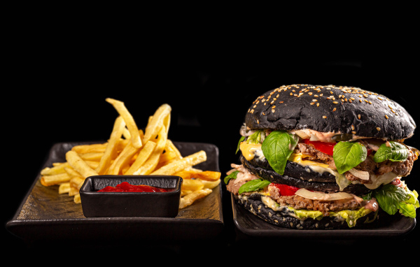 Большой черный гамбургер с картофелем фри и кетчупом 