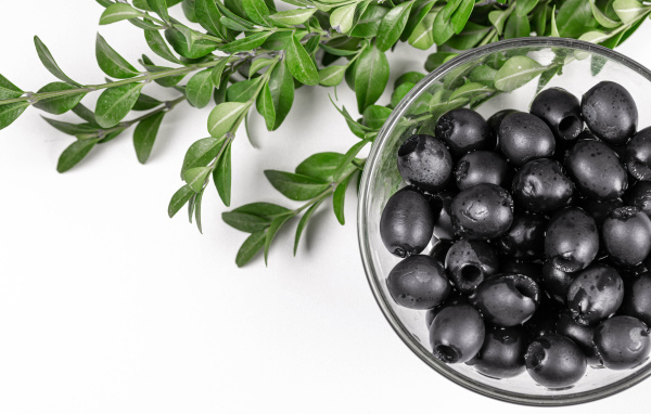 Черные маслины с веткой на белом фоне