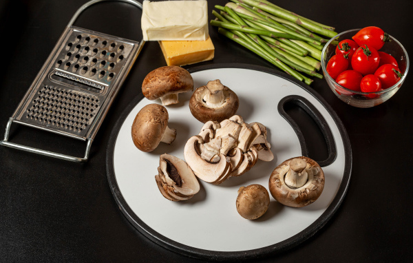 Шампиньоны на столе со спаржей и помидорами 