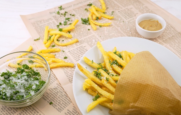 Картофель фри с зеленью на газете