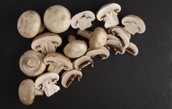 Свежие нарезанные шампиньоны на сером фоне