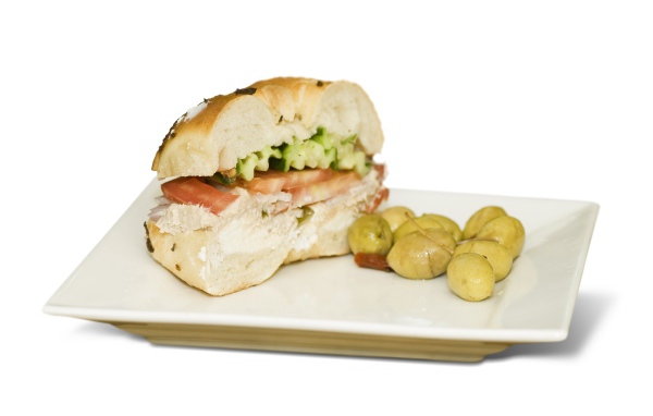 Половина гамбургера на тарелке с оливками