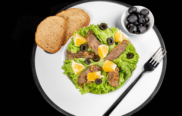 Листья салата с мясом на столе с хлебом