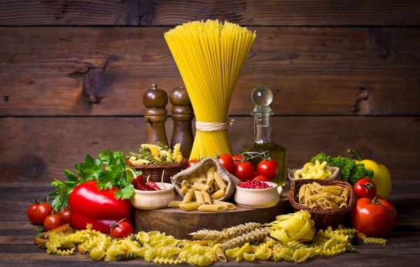 Много макаронных изделий на столе с овощами 