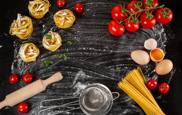 Паста с помидорами и яйцами на черном столе 