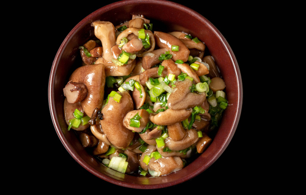 Маринованные маслята с зеленью в тарелке