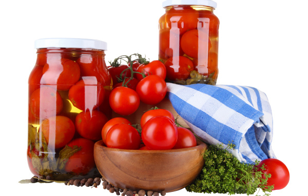 Маринованные помидоры в банках на столе со свежими
