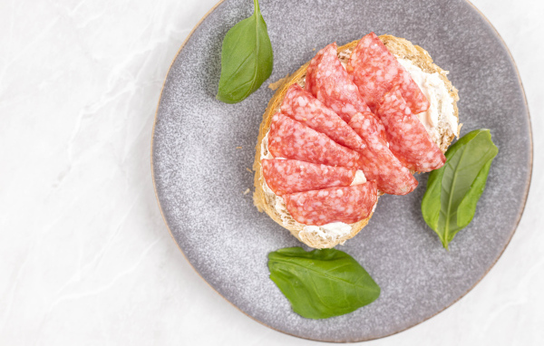 Бутерброд с маслом и колбасой на тарелке