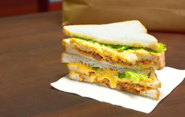 Сэндвич с сыром и листьями салата на столе