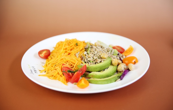 Овощи в белой тарелке на оранжевом фоне 