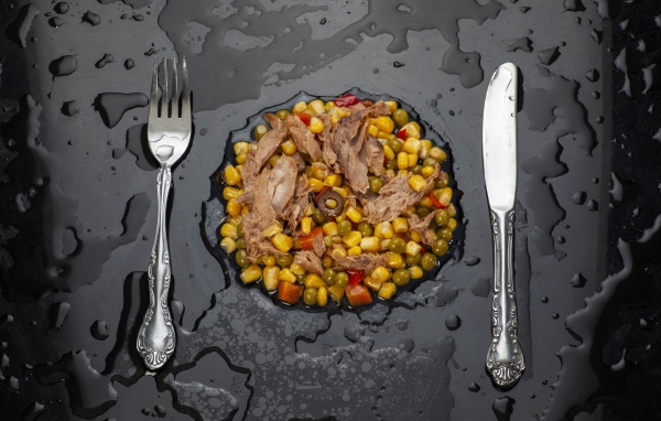 Овощи с мясом и столовыми приборами на черной поверхности