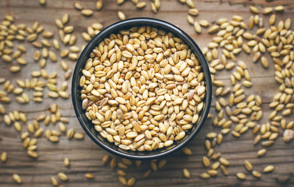 Зерна пшеницы в черной кружке на столе 