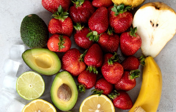 Авокадо, клубника,лимон и груша на сером столе 