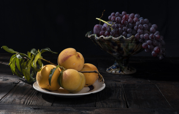 Красивые сочные персики на столе с виноградом