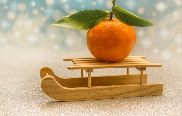 Большой оранжевый мандарин на маленьких санках