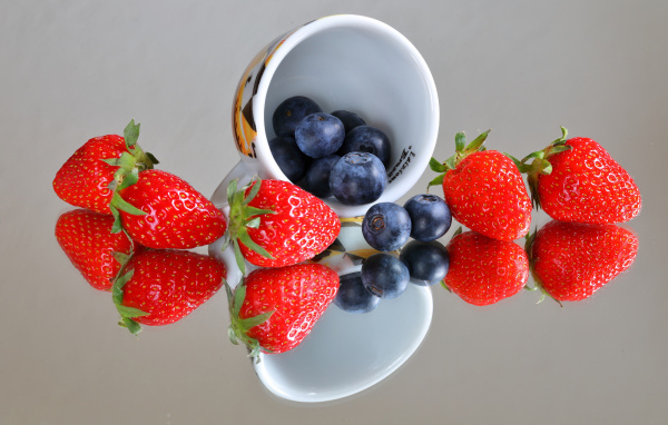 Чашка с ягодами черники и клубники на столе