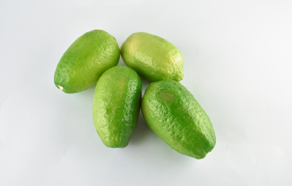 Четыре зеленых лимона на белом фоне
