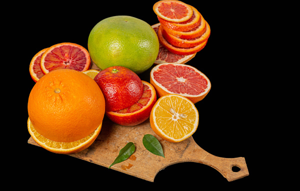 Свежие нарезанные цитрусовые фрукты на черном фоне