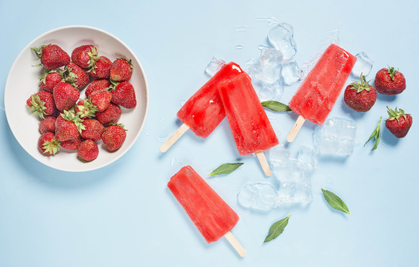 Мороженое со льдом и ягодами клубники на голубом фоне 