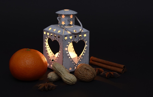 Мандарин, орехи, специи и фонарь на черном фоне