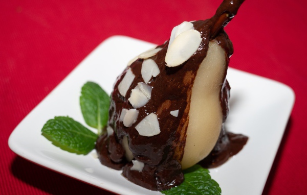 Pear on a white plate with chocolate on a red background