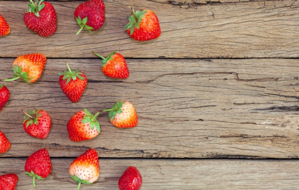 Спелая красная клубника лежит на деревянном столе
