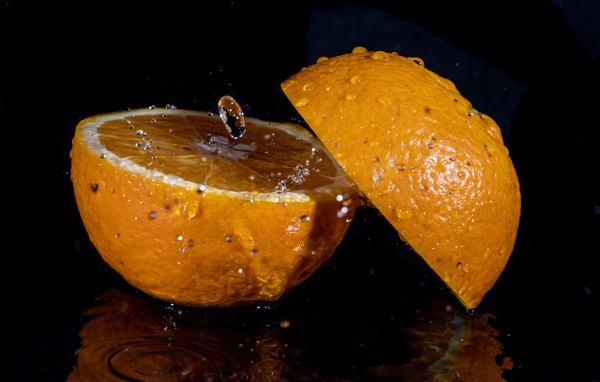 Две половины апельсина на черном фоне 