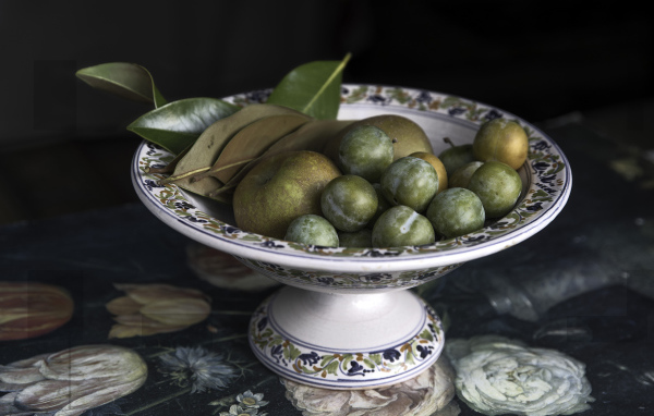 Белые сливы и зеленые яблоки в вазе на столе 