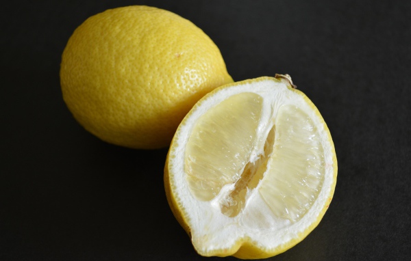 Целый лимон и половина на черной поверхности